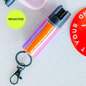 A reflective pepper spray in color opal coral, attached to a keychain.